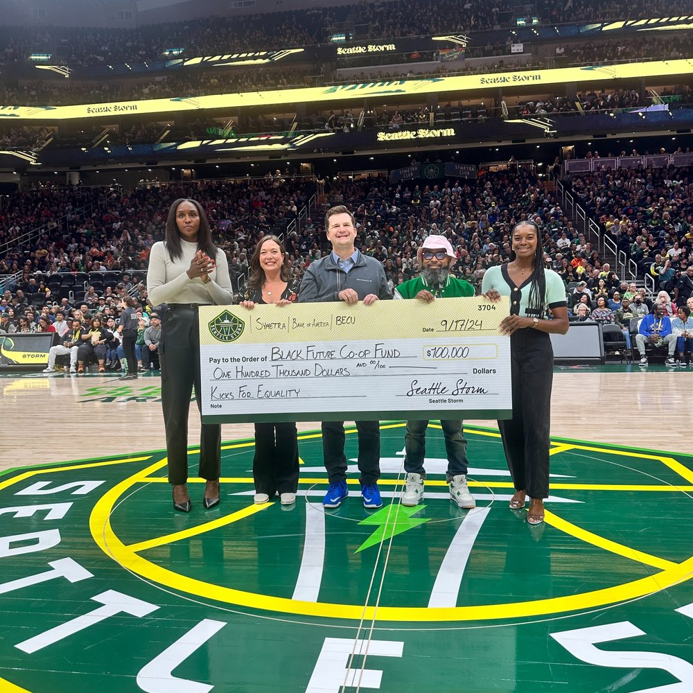 Representatives from the Black Future Co-op Fund receiving a check at a Seattle Storm game
